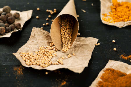 Paper bag with white mustard seeds among other spices