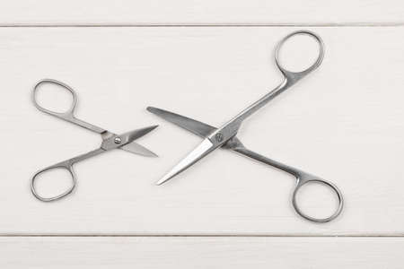 Big and small metal scissors on a white wooden table, top viewの写真素材