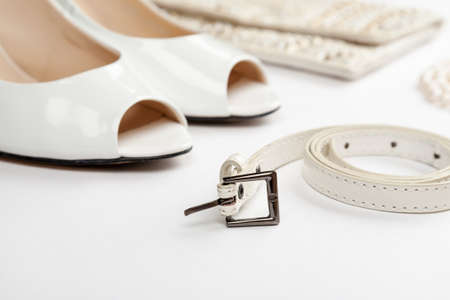 Female white shoes, bag, belt and pearl necklace on a white backgroundの写真素材