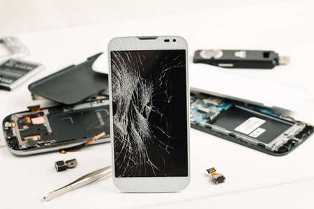 Cell phone with broken display among disassembled gadgets