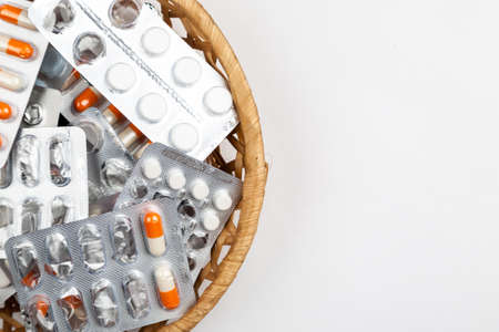 medicines in blister packs in a wicker basket on a white backgroundの写真素材
