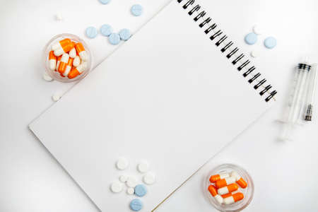 Blank notepad among different medications on a white background, template for textの写真素材