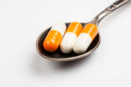 Medications in a metal spoon on a white background