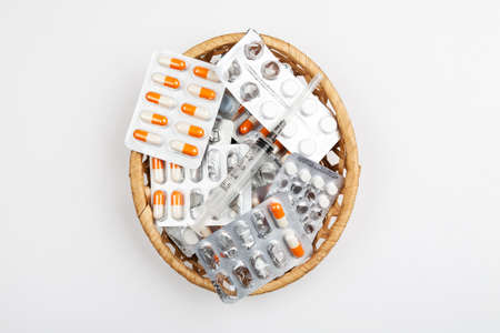 medicines in blister packs in a wicker basket on a white backgroundの写真素材