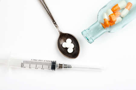 Medications and pills with spoon and syringe on a white backgroundの写真素材
