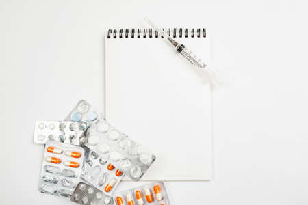 Blank notepad among different medications on a white background, template for textの写真素材
