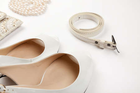 Female white shoes, bag, belt and pearl necklace on a white backgroundの写真素材
