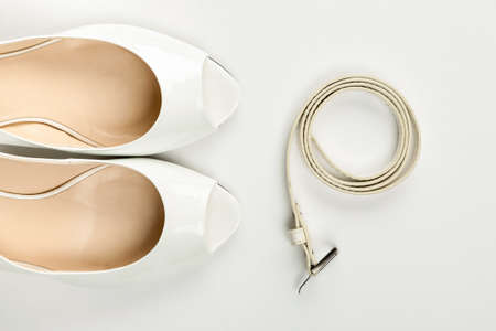 Female white shoes and belt on a white background top view