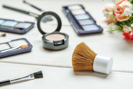 Big cosmetic brush among makeup items on a white wooden tableの写真素材