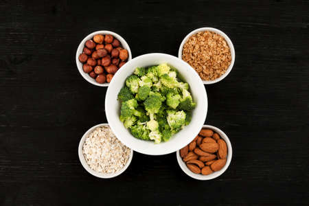 Nuts and cereals in a white ceramic dishes with broccoliの写真素材