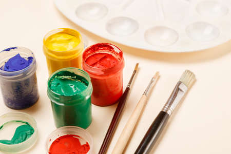 Paintbrushes, open paint jars and palette on a table, side view, copy spaceの写真素材