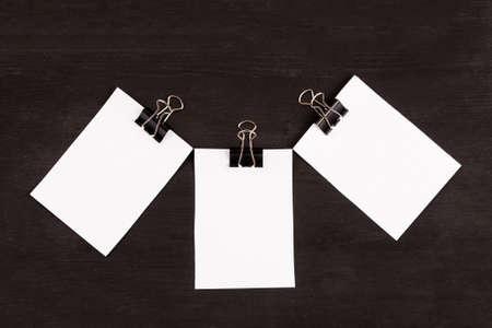 Blank sheets of white paper with paper clip on a black backgroundの写真素材