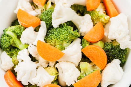 Fresh salad with raw broccoli, cauliflower and carrot in a white dishの写真素材