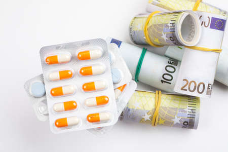 Different medications and pills with euro banknotes on a white backgroundの写真素材