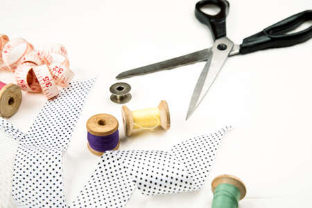Set of tools and accessories for sewing and needlework with threads in spools, needles, measuring tape and other items on a white backgroundの写真素材
