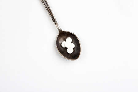 Medications in a metal spoon on a white backgroundの写真素材