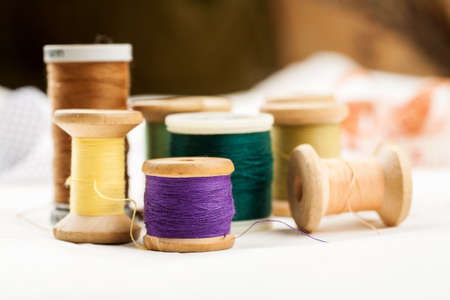 Set of tools and accessories for sewing and needlework with threads in spools, needles, measuring tape and other items on a white backgroundの写真素材