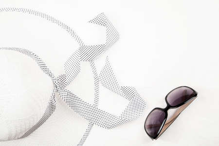 Women's hat and sunglasses on a white background, top view, text space