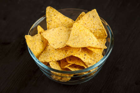 Corn chips nachos in a glass bowl on a black backgroundの写真素材