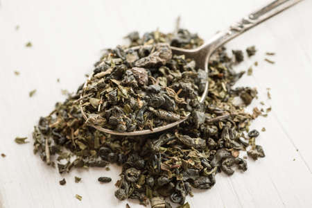 Dry tea in a metal spoon on a white wooden tableの写真素材