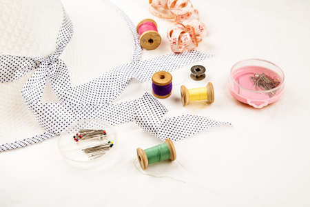 Set of tools and accessories for sewing and needlework with threads in spools, needles, measuring tape and other items on a white backgroundの写真素材