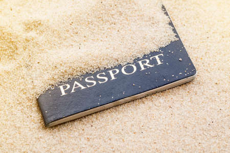Blue passport covered with sand on a beachの写真素材