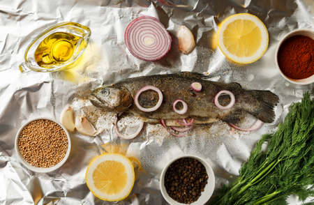 Fresh fish with herbs and spices on crumpled aluminum foil , top viewの写真素材