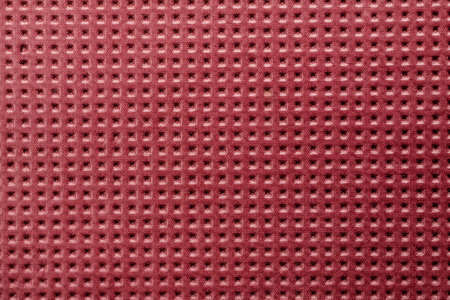 Red plastic material with symmetric square holes, abstract texture