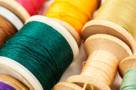 Different colour thread on wooden spools on a white background, macro shotの写真素材