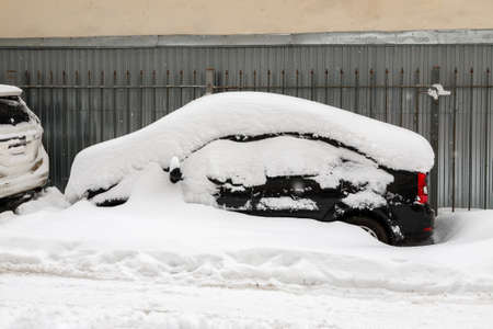 Black car covered with snow on a parkingの写真素材