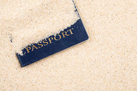 Blue passport covered with sand on a beach, top viewの写真素材