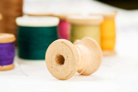 Set of tools and accessories for sewing and needlework with threads in spools, needles, measuring tape and other items on a white backgroundの写真素材