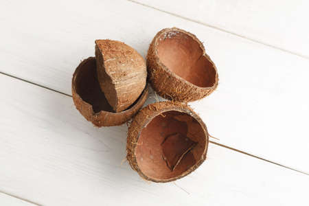 Empty coconut shells on a white wooden table, top view