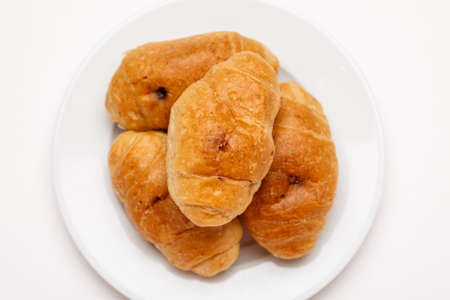 Fresh croissant in a white plate on a white table, top viewの写真素材