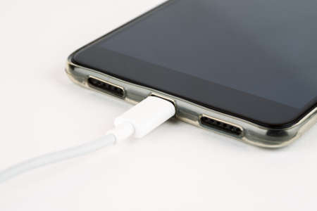 Charging smartphone in silicon bumper on a white background closeup shot