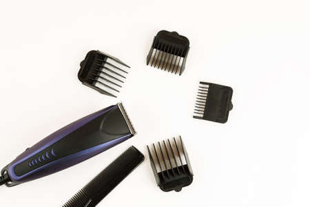Electric hair clipper with different size attachments on a white background, top view