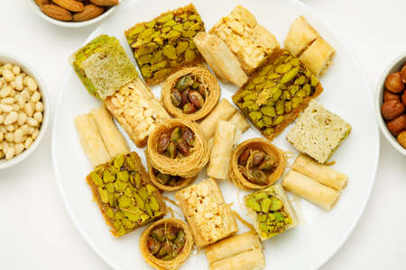Traditional oriental sweets in white plate with different nuts on a white table, top viewの写真素材