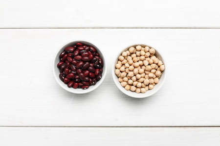 Different beans in bowls on a white wooden table, top viewの写真素材