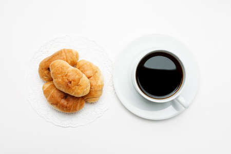 Fresh croissant in a white plate and cup of coffee, top viewの写真素材
