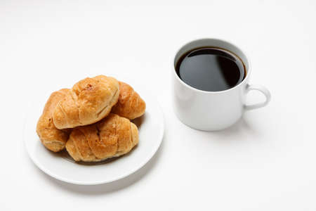 Fresh croissant in a white plate and cup of coffee, top viewの写真素材