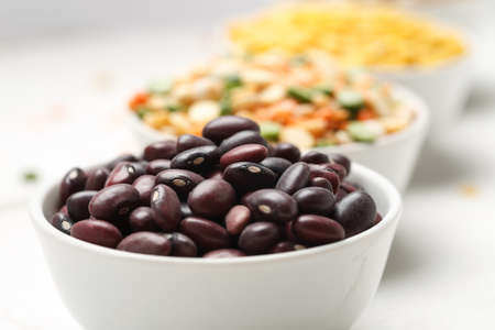 Different beans in bowls on a white wooden tableの写真素材