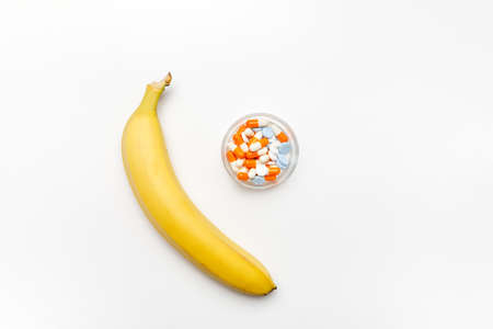 Fresh banana and pills on a white background, top viewの写真素材