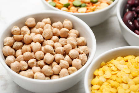 Chickpea and other beans in white bowls on a wooden tableの写真素材