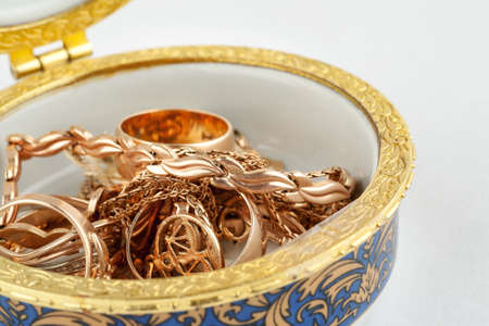 Small ceramic box with gold jewelry in it on white background, macroの写真素材