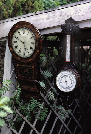 Wall clock and thermometer hanging outdoorの写真素材