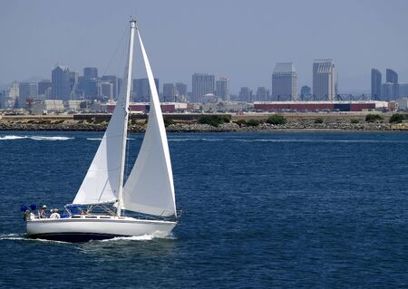 A sailboat speeds along in San Diego Harbor, Californiaの写真素材