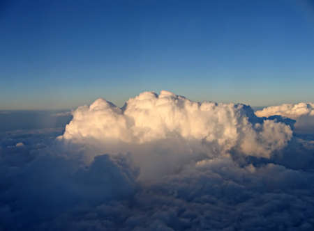 Puffy clouds with sunlight just starting to touch them in a pretty blue skyの写真素材