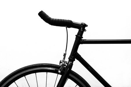 Black and white image of a bicycle against a white wall background.の写真素材