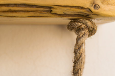 Close up of a rope tied on a wooden shelf in a roomの写真素材