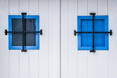 blue window on white wooden wall with black frame, close up.の写真素材